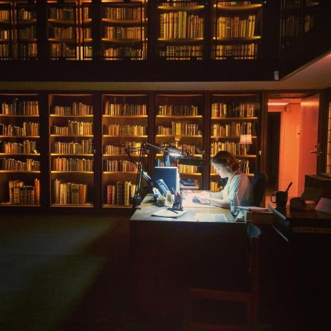 Woman in a darkened library working on a computer